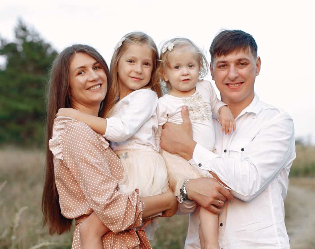 Smiling family posed outdoors for a church directory family photo.
