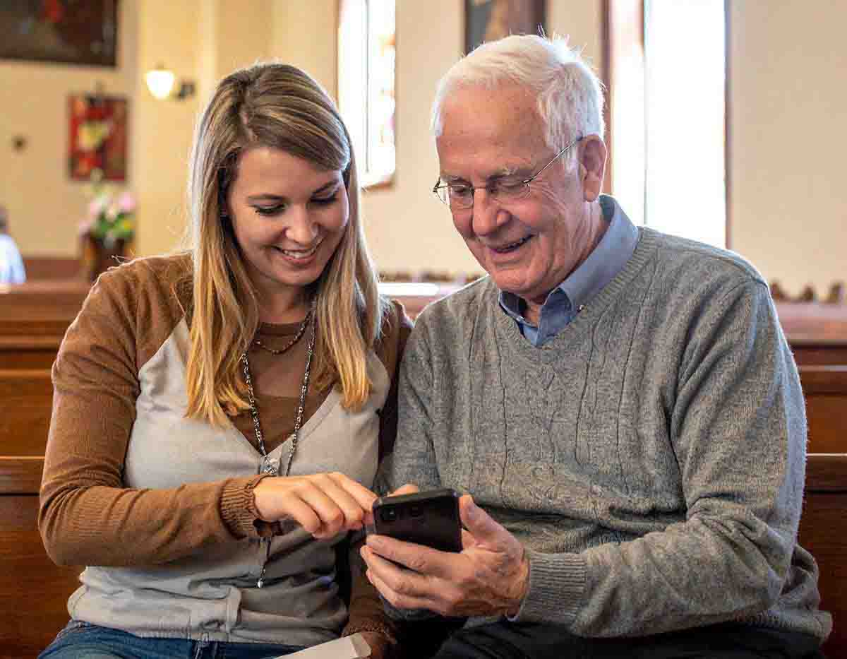 Young adult assisting senior with church directory on mobile phone